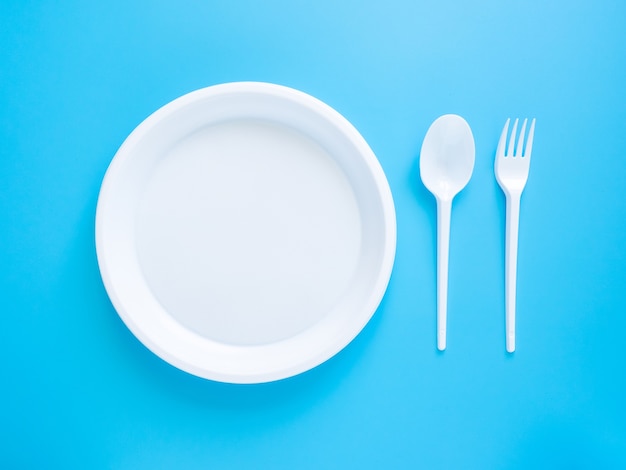 Vajilla desechable, cucharas de plástico blanco, tenedores, vasos y platos aislados