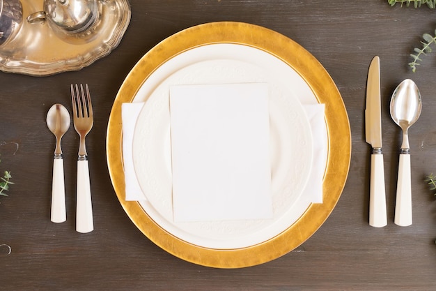 Vajilla - juego de platos blancos y dorados y platería sobre mesa de madera oscura