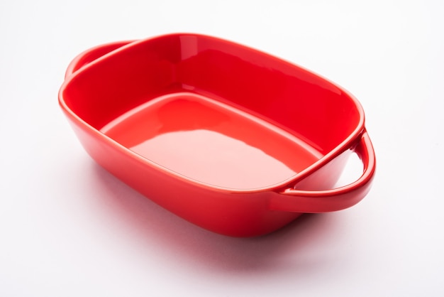Vajilla vacía - cuenco de cerámica roja o utensilios para hornear sin comida sobre fondo blanco.