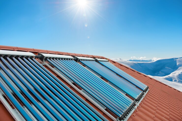 Vakuumkollektoren - Solare Wasserheizrohre auf dem Dach des Hauses mit Sonne und Schneebergen