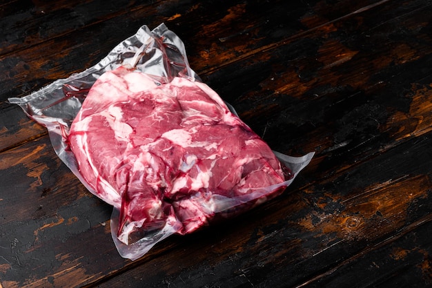 Vakuumverpacktes Fleisch auf altem dunklem Holztischhintergrund mit Kopierplatz für Text