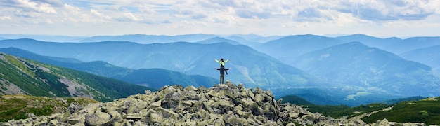 Vale da montanha do panorama com vista traseira das florestas verdes da menina está sentada nos ombros do cara com os braços abertos