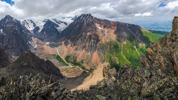 Vale da montanha pitoresca. Couloir perigoso. Paisagem verde ensolarada colorida com silhuetas de grandes montanhas rochosas e desfiladeiro profundo épico. Montanhas Altai.