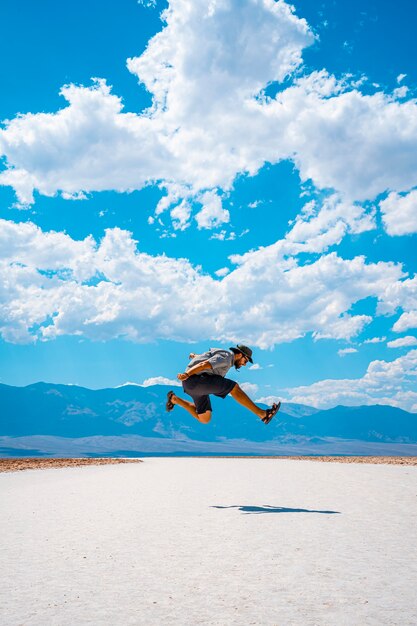 Vale da Morte, Califórnia, Estados Unidos. Um jovem pulando com uma camisa azul no sal branco de Badwater Basin