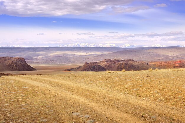 Vale de Chui nas montanhas de Altai Penhascos rochosos rastros de carros na planície contra t
