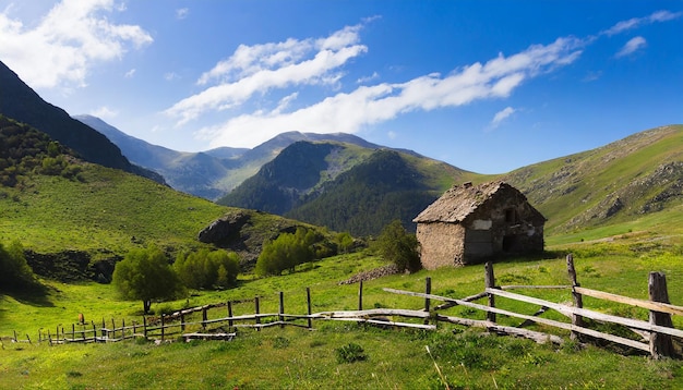 Foto vale de montanha verde com velha casa em ruínas e cerca de madeira