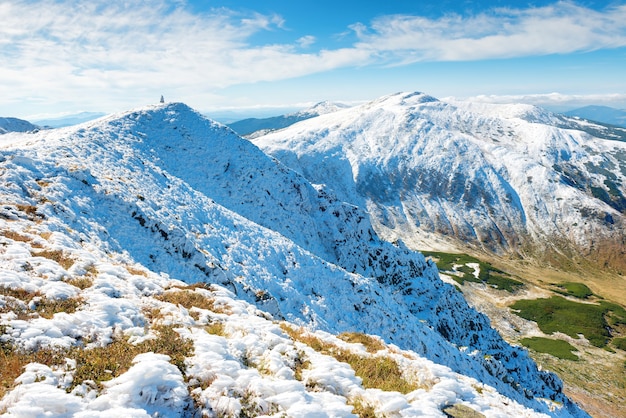 Vale verde e picos brancos de montanhas na neve. Paisagem de inverno