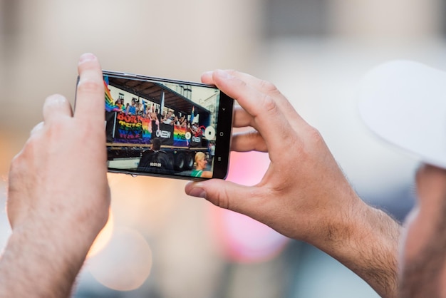 Foto valencia españa 28 de junio de 2022 espectador grabando el día del desfile del orgullo con su smartphone