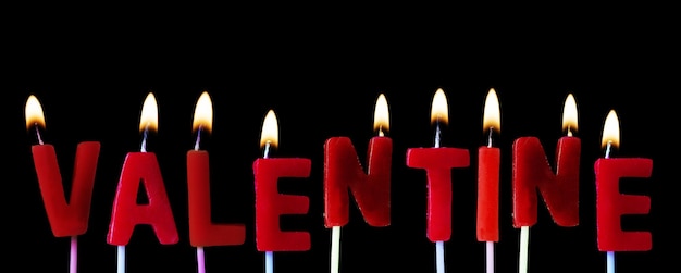 Valentine buchstabierte sich in roten Kerzen vor einem schwarzen Hintergrund