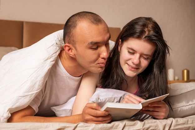 Valentine glückliches Paar liegt auf dem Bett und liest ein Buch