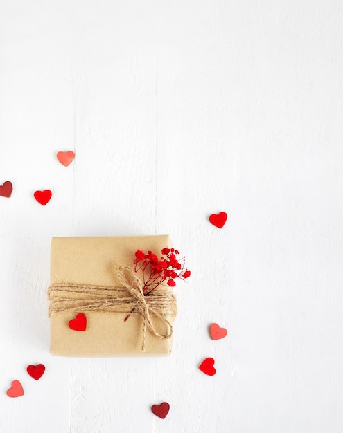 Valentine39s Day Flatlay Geschenkbox aus Bastelpapier mit Herzen und roten Blumen auf weißem Holzhintergrund