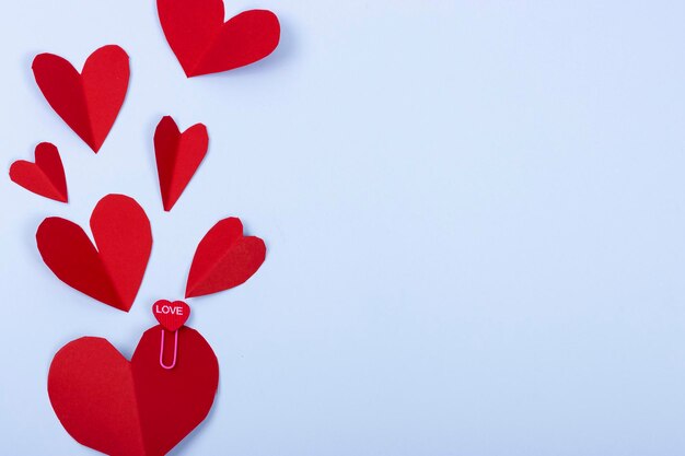 Valentine39s Day Hintergrund Rote Herzen auf hellblauem Hintergrund Büroklammer mit Herzform und dem Wort quotlovequot darauf geschrieben