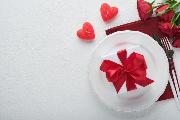 Valentines Day romantische Tischdekoration Leer oder Nahaufnahme eines Abendessens schwarze Platte, Messer, Gabel und dekorative Seidenherzen auf weißem Hintergrund Ferienkonzept Kopieren Sie Platz für Inschriften