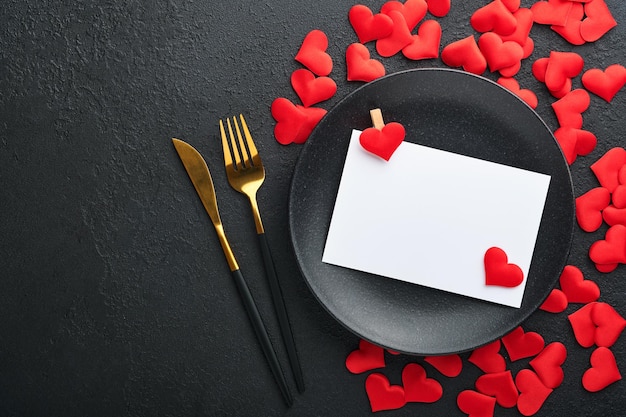 Valentines Day romantische Tischeinstellung Leer oder Nahaufnahme eines Abendessens schwarze Messergabel und dekorative Seidenherzen auf schwarzem Hintergrund Ferienkonzept Kopieren Sie Platz für Inschriften