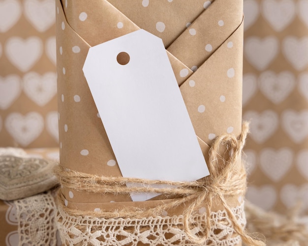 Foto valentins-kraftpapier verpacktes geschenk mit vertikalem geschenkanhänger und herzen aus nächster nähe. frühlingsszene mit leerem etikett. rustikales, schickes oder böhmisches mockup, kopierraum