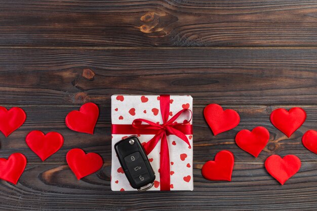 Valentinsgruß oder anderes handgemachtes Geschenk des Feiertags im Papier mit roten Herzen, Autoschlüsseln und Geschenkkasten in der Feiertagsverpackung