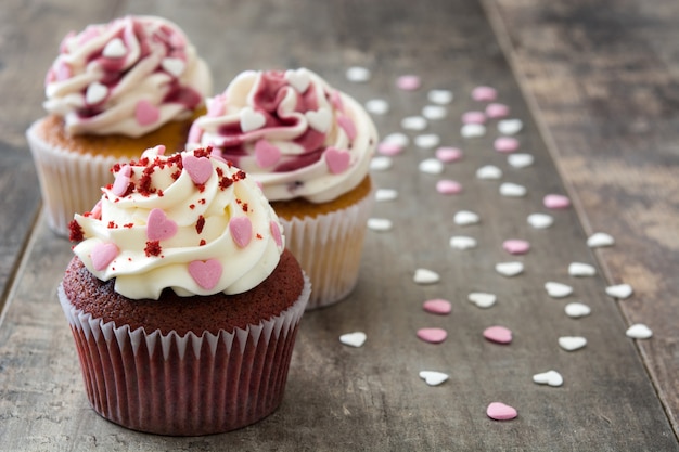 Valentinsgrußkleine kuchen verziert mit Schatzen auf Holztischkopienraum