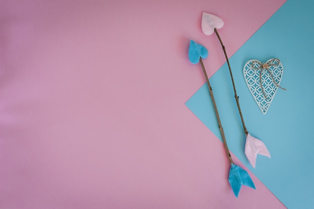 Valentinsgrußtageszweigpfeile auf rosa und blauem Hintergrund mit Herzen