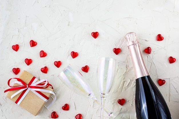 Valentinskarte mit Champagnergläsern und Flasche, Herz und Geschenk auf weißem Hintergrund