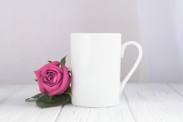 Valentinstag-Becher, Tasse auf dem Holztisch und weißer Hintergrund mit roter Rose.