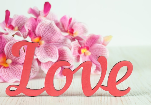 Valentinstag Buchstaben Liebe und rosa Orchidee Blumen auf weißem Holz Hintergrund