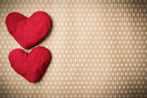 Valentinstag. Bunte gestrickte Herzen auf einem Jahrgang in Tupfen. Rotes Herz.