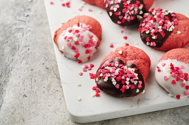 Valentinstag Cookies Shortbread Cookies mit Glasur weiße und dunkle Schokolade und Herz Streuseln auf Platte auf weißem Hintergrund Muttertag Womans Tag Süße Feiertage backen Draufsicht