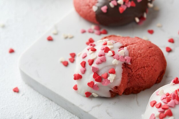 Valentinstag Cookies Shortbread Cookies mit Glasur weiße und dunkle Schokolade und Herz Streuseln auf Platte auf weißem Hintergrund Muttertag Womans Tag Süße Feiertage backen Draufsicht