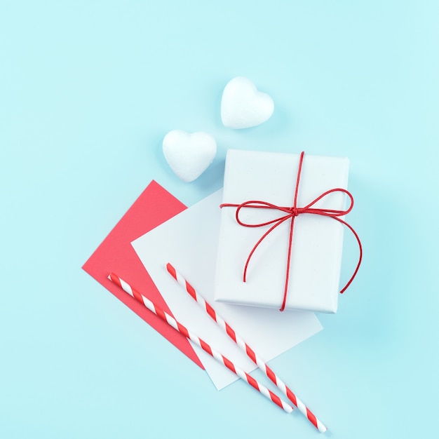 Valentinstag-Designkonzept - Rote, weiße verpackte Geschenkbox lokalisiert auf hellblauem Farbhintergrund