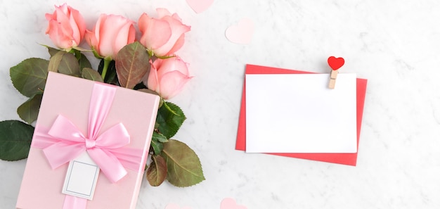 Valentinstag-Designkonzepthintergrund mit rosa Rosenblume und Geschenkbox auf weißem Marmorhintergrund