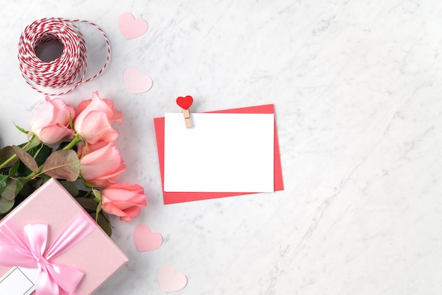 Valentinstag-Designkonzepthintergrund mit rosa Rosenblume und Geschenkbox auf weißem Marmorhintergrund