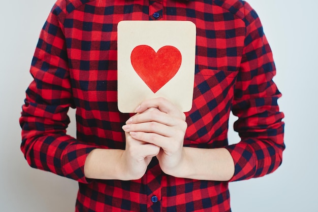 Valentinstag, ein junges blondes Mädchen, das eine Karte mit einem Herzen in den Händen hält