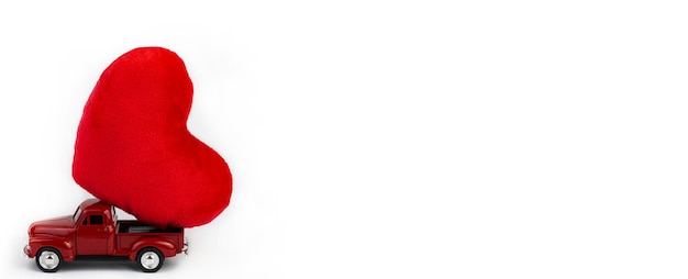 Valentinstag. Ein rotes Auto trägt ein Herz auf weißem Hintergrund. Breites Banner, Kopierraum, Postkarte.