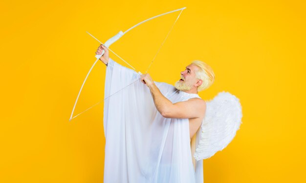 Foto valentinstag feiern pfeil der liebe lächelnde blonde mann in engel kostüm schießen liebe pfeil