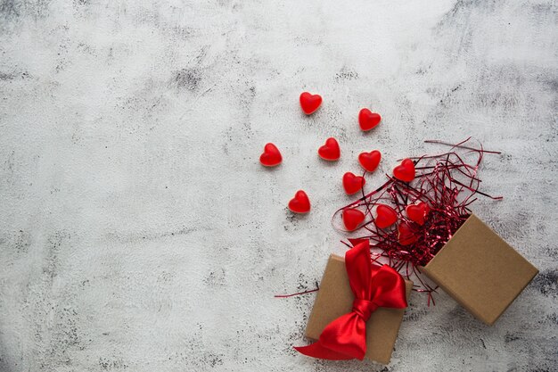 Valentinstag, Geschenkbox aus Kraftpapier mit einer roten Herzsüßigkeit. Grauer Hintergrund.