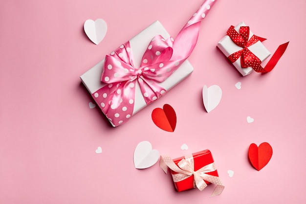 Valentinstag Geschenkboxen mit Papierherzen auf rosa Hintergrund