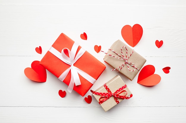 Valentinstag Geschenkboxen und rote Papierherzen auf weißem Holztisch