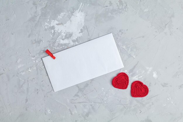 Foto valentinstag-grußkarte mit zwei handgefertigten herzen und papierumschlag für ihren text auf grauer betonoberfläche, draufsicht, flacher kopierraum