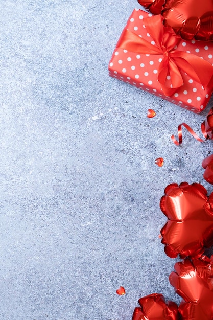 Valentinstag-Grußkarte temlate Rote Luftballons in Herzform und Geschenkbox auf konkretem Hintergrund mit Kopierraum