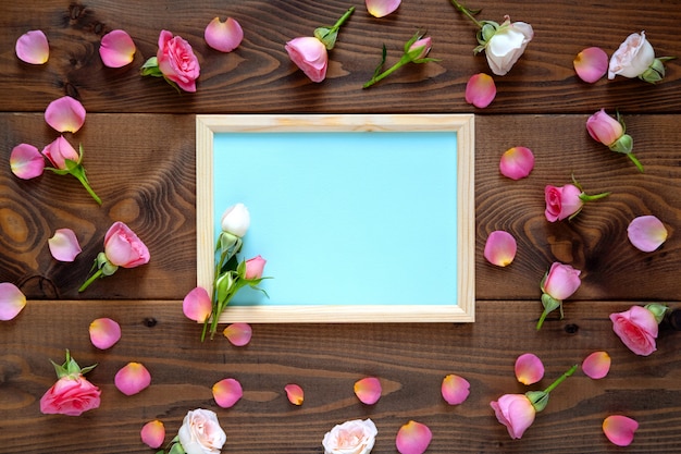 Valentinstag Hintergrund. Das Blumenmuster des runden Rahmens, das von den rosa und beige Rosen, Grün gemacht wird, verlässt auf hölzernem Hintergrund. Flachgelegt, Draufsicht.