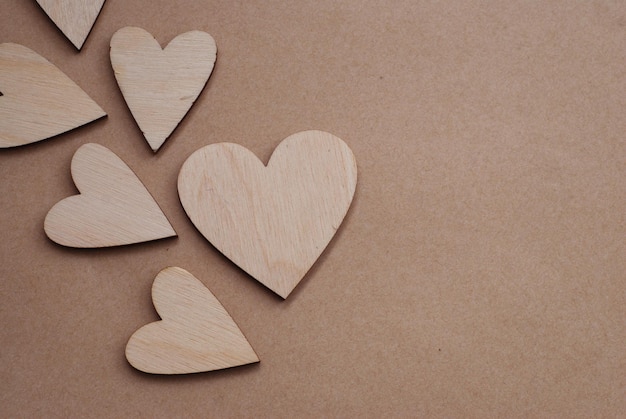 Valentinstag Hintergrund mit lasergeschnittenen Holzherzen auf neutralem Craft Paper Background mit Copy Paste. Rustikaler Liebeshintergrund.