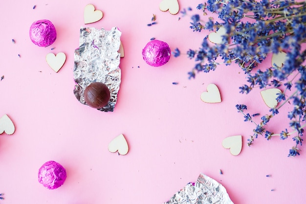 Valentinstag Hintergrund. Reihe von Holzherzen auf rosa Hintergrund, Seitenansicht eines Zweiges von trockenem Lavendel. Valentinstag-Konzept. Draufsicht, Platz für Beschriftung, Werbung