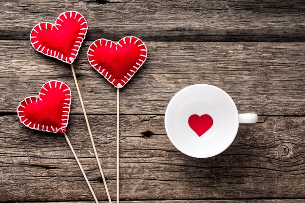 Valentinstag Hintergrund. Rote Herzen, Band und Tasse auf Holzhintergrund.