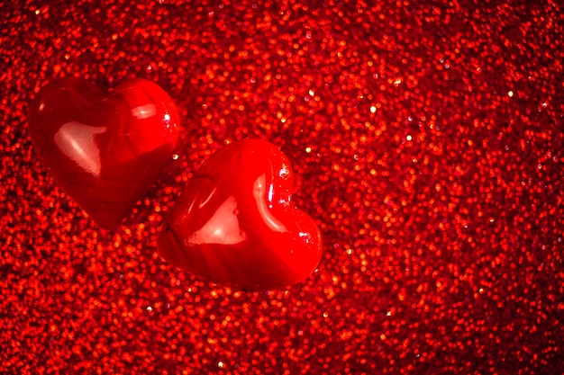 Valentinstag Hintergrund, zwei rote Herzen auf rotem Glitzerhintergrund. Raumfoto kopieren