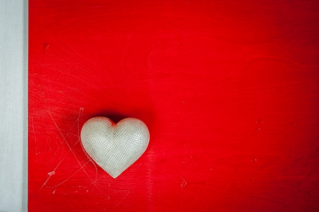 Valentinstag. Hochzeitstag. Silbernes Herz auf rotem hölzernem Hintergrund.
