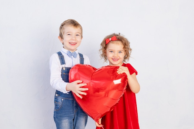 Valentinstag Kinder. Junge und Mädchen halten großen roten Herzball