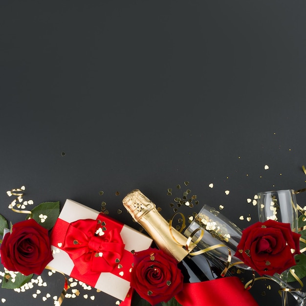 Valentinstag Komposition flach Draufsicht mit Geschenkbox Rosenblüten Geschenk Champagner und Herzen Gestaltungselement auf schwarzem Hintergrund mit Platz für Text kopieren