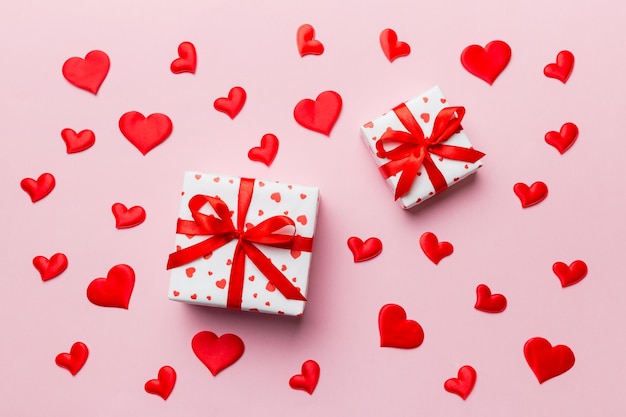 Valentinstag-Komposition Hintergrund: rote Geschenkbox mit Schleife und Herz. Weihnachtsgeschenk. Sicht von oben. Feiertagsgrußkarte.