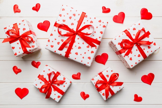 Valentinstag-Komposition Hintergrund: rote Geschenkbox mit Schleife und Herz. Weihnachtsgeschenk. Sicht von oben. Feiertagsgrußkarte.