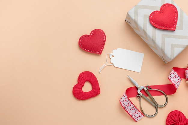 Valentinstag Komposition mit Geschenken und handgemachten Herzen. Draufsicht mit leerem Tag für Text.